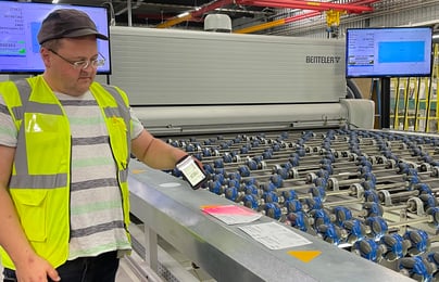 An employee stands at a workstation and scans the lites.